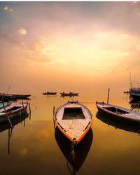 Boat moored in sea against sky during sunset