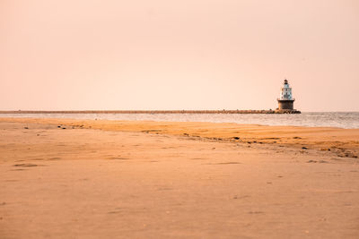 Lighthouse on beach against sky