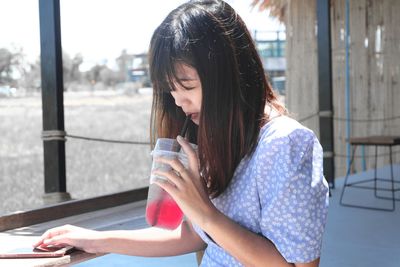 Young woman using phone while sitting outdoors