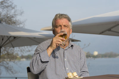 Portrait of senior man drinking beer at restaurant
