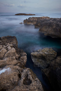 Rocks on sea shore against sky