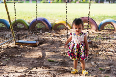 Child, playing, standing next to the swing at the playground.