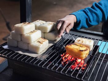 Close-up of hand holding ice cream on barbecue grill