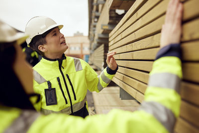 Female workers examining planks stacked at industry