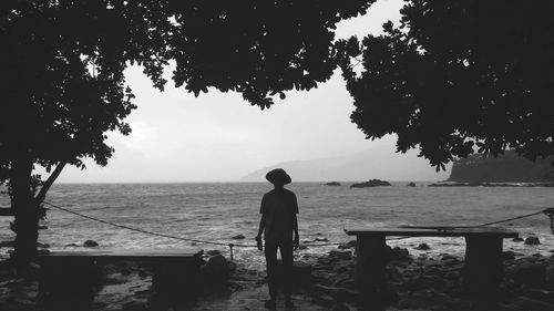 Rear view of man looking at sea against sky