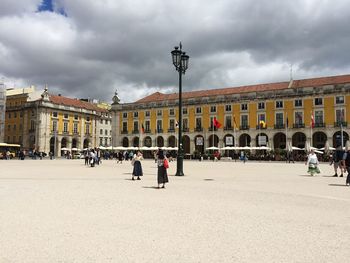 Group of people in front of building against cloudy sky