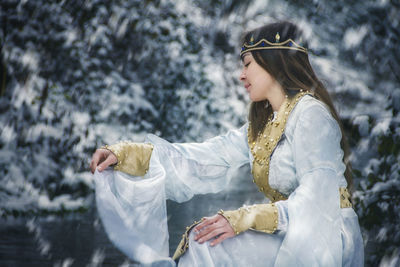 Woman in costume sitting against trees