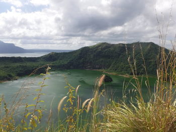 Scenic view of lake and mountains against cloudy sky