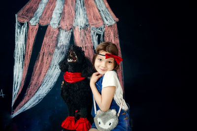 European kid girl plays circus theater with black poodle. artistry and training of pet dog. 