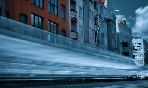 Blurred motion of buildings by road against sky