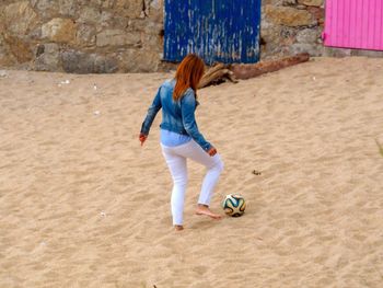 Full length of woman playing soccer at beach