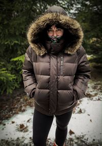 Portrait of young woman standing on snow covered land