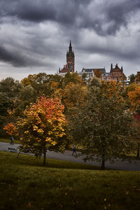 Trees by historic building against sky during autumn