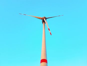 Low angle view of wind turbine against clear blue sky