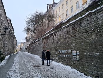 Rear view of people walking on street in city during winter