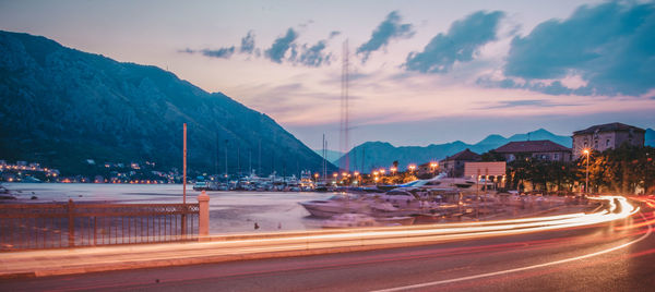 Light trails on road by mountain against sky at night