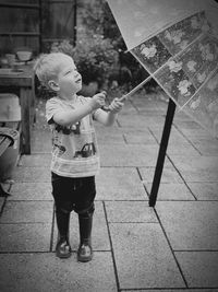 Full length of boy holding umbrella on street