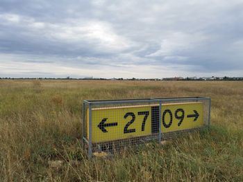 Information sign on field against sky