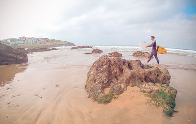 Woman standing on beach against sky