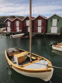 Boats moored in sea by houses against sky