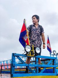 Man holding flag standing against sky