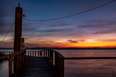 Pier over sea against sky during sunset