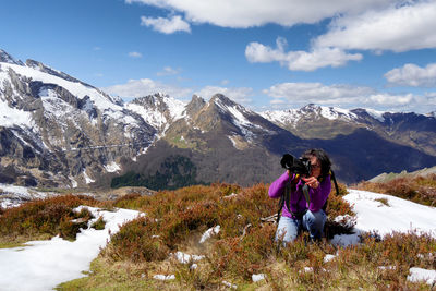 Woman photographing on mountain during winter