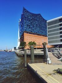 Building by river against clear blue sky