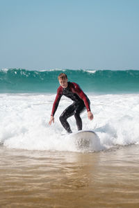 Full length of man jumping on sea shore against sky