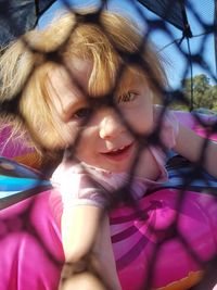 Portrait of girl on inflatable ring seen through fence