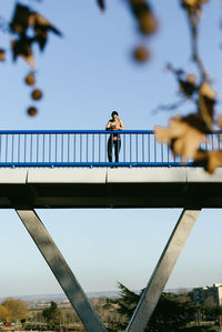 Man on footbridge against sky