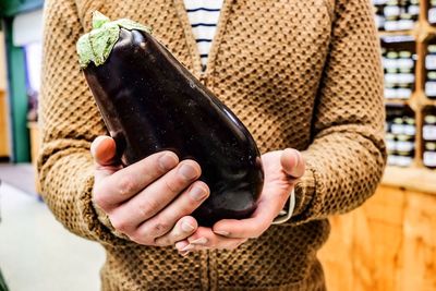 Midsection of man holding eggplant