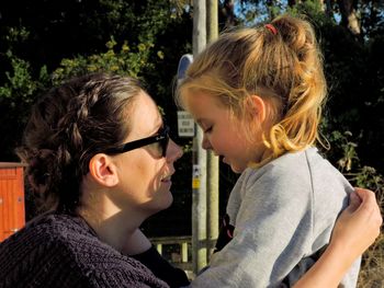 Close-up of mother with daughter against trees