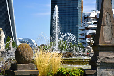 Statue by fountain against buildings in city