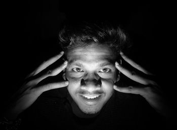 Portrait of young man against black background