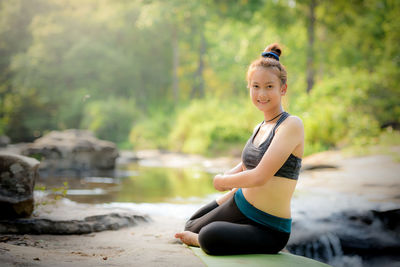 Full length of woman sitting by water