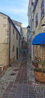 Footpath amidst buildings in city against sky