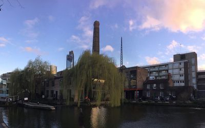 Buildings by river against sky in city