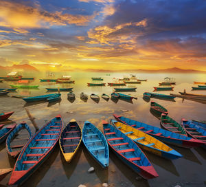High angle view of boats moored in sea against cloudy sky during sunset