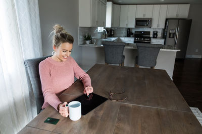 Woman holding coffee cup on table at home