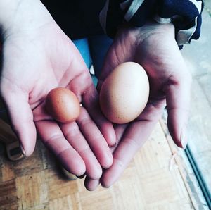 Cropped hands of person holding brown eggs over table 