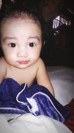 Portrait of cute baby girl on bed at home