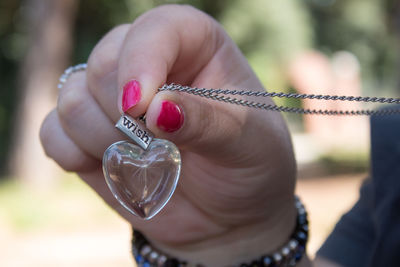 Cropped hand of woman holding heart shape locket