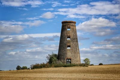 Lighthouse on field against sky