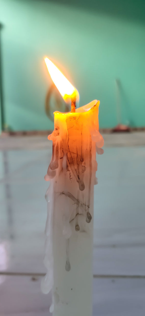 CLOSE-UP OF LIT CANDLES ON GLASS