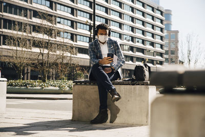 Businessman with face mask using mobile phone