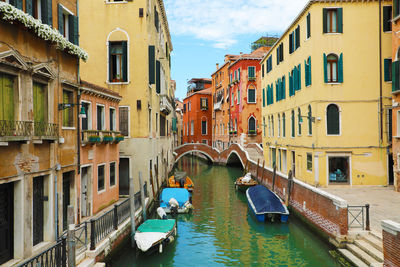 Boats moored in canal amidst buildings in city