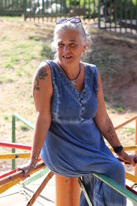 Portrait of smiling woman sitting on railing