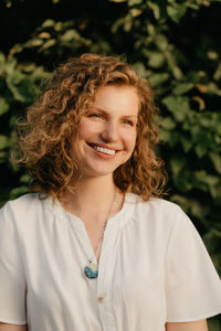 Portrait of young woman standing against plants