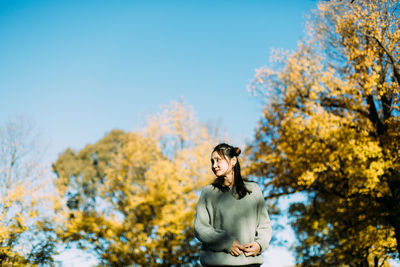 Woman standing by trees against sky